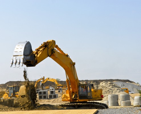 Yellow bulldozer machines digging and moving earth at construction site